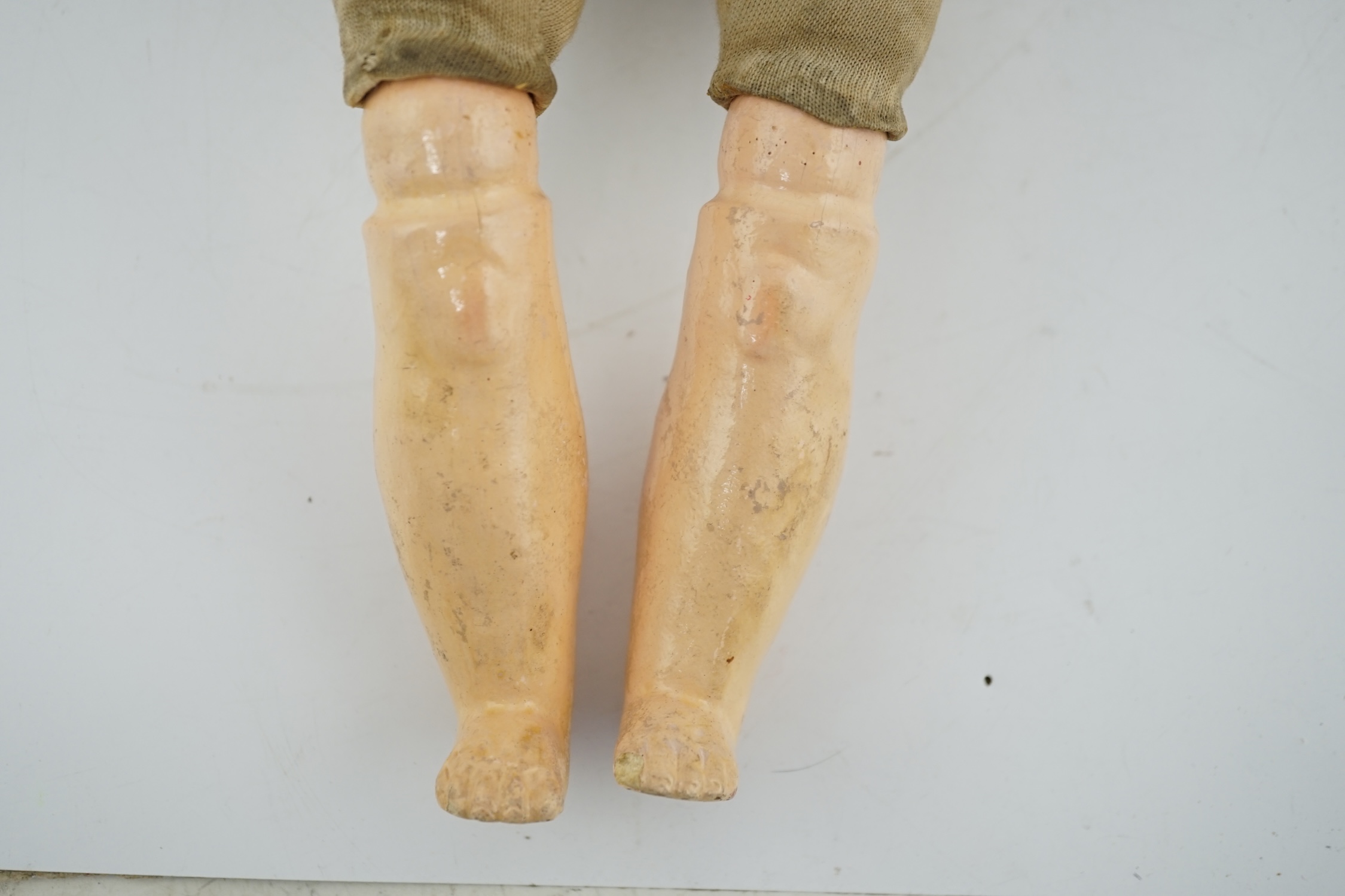 A late 19th century French biscuit head doll, possibly Simon & Halbig, with cloth body, bisque hands, 45cm high, eye and ear chip